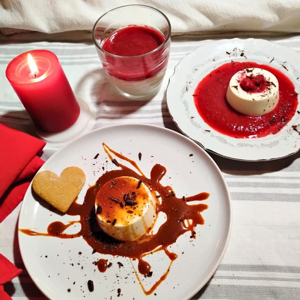 display of three versions of panna cotta to demonstrate the versatility of this desert. One Panna cotta is surrounded wtih raspberry sauce, one with cajeta on top and around, one in a glass with raspberry sauce on top and a candle sits next to it all.