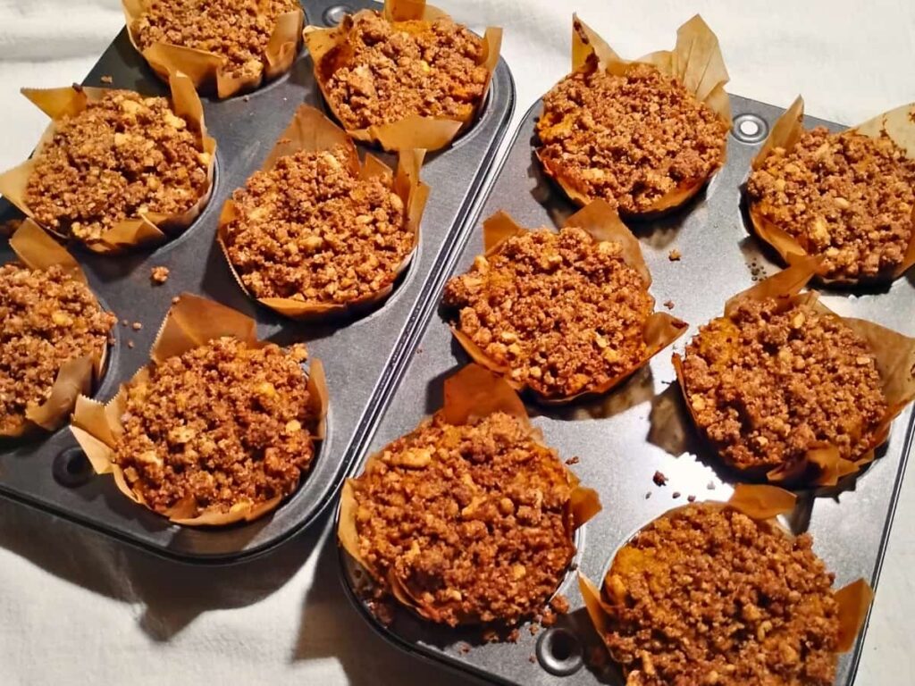 A couple of muffin pans filled with fresh baked muffins in muffin sleeves.