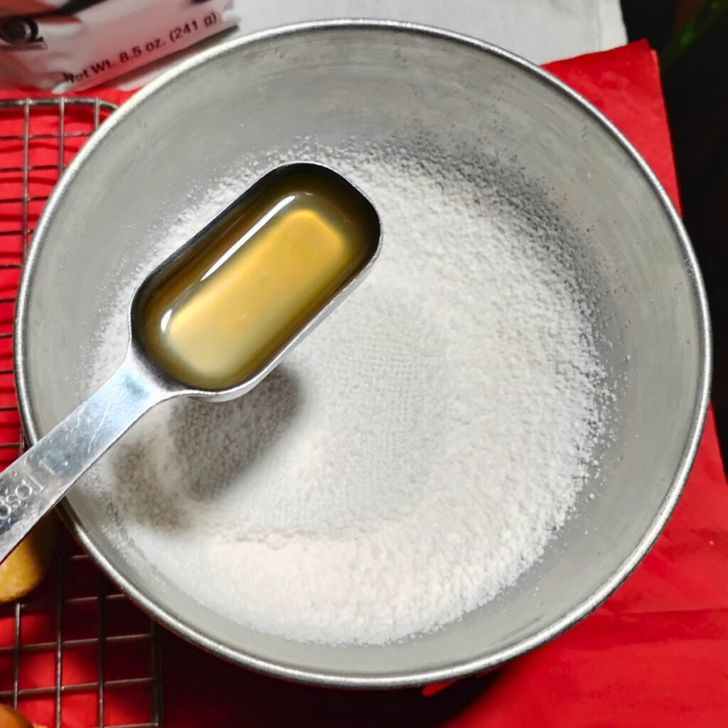 a bowl with powdered sugar and a spoon filled with lemon juice to add.