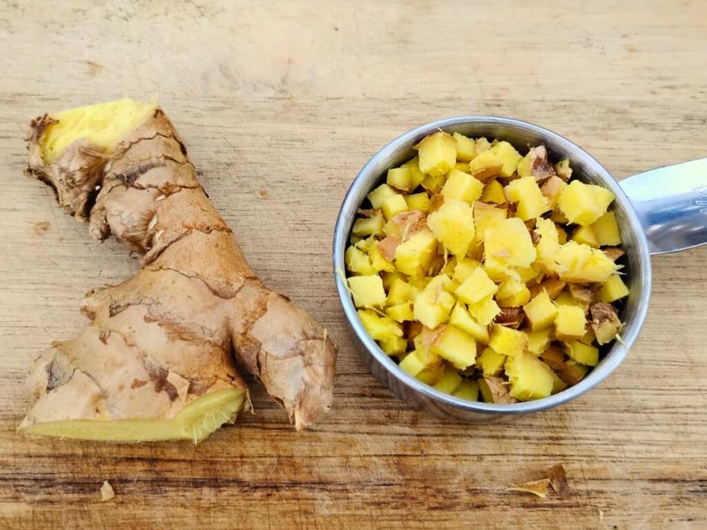 ginger chopped in a measuring cup and a chunk of fresh ginger next to it.