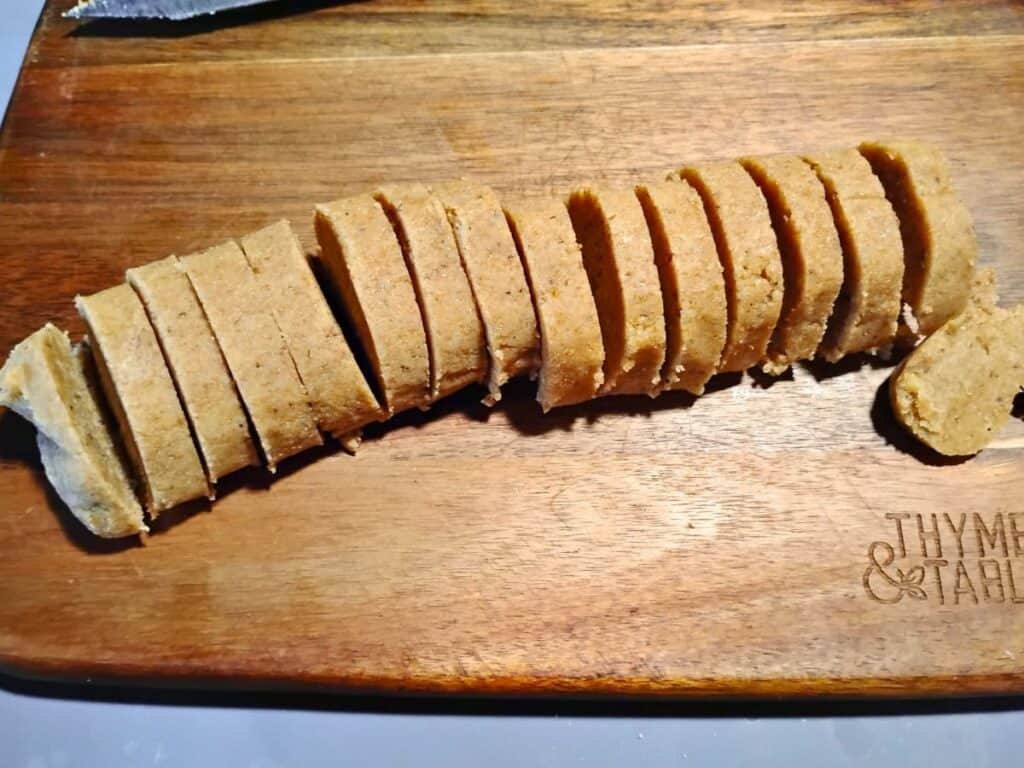 a roll of cookie dough that's cut into 16 slices on a cutting board.