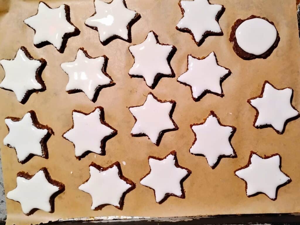 parchment lined baking sheet with frosted cinnamon star cookies ready for baking.
