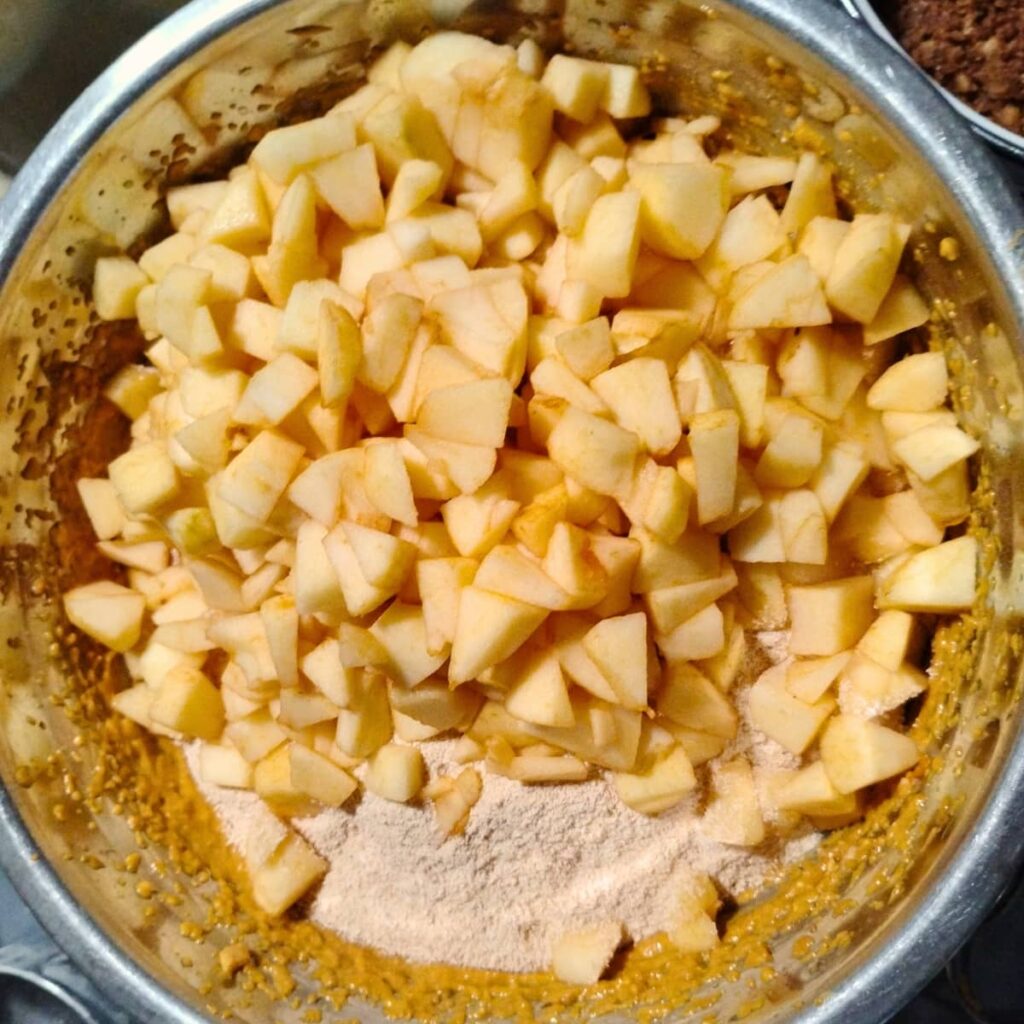 apples and flour are added to the batter in the bowl.
