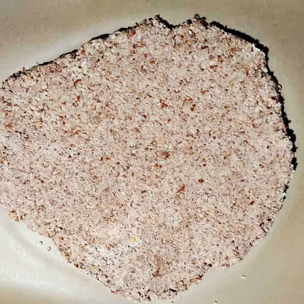 almond meringue dough rolled out on a piece of parchment.