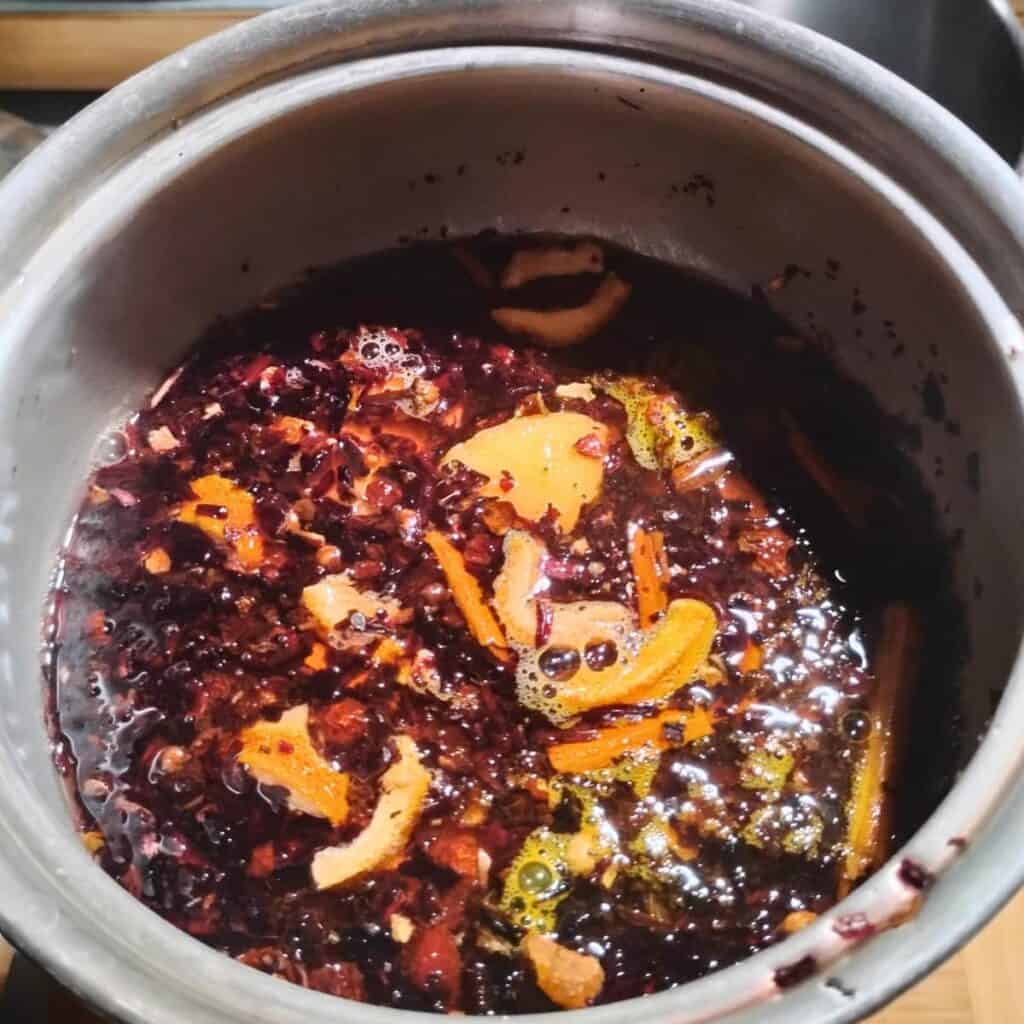 photo shows rosehips, hibiscus, and spices in a pot.