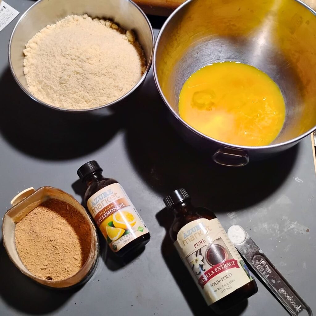 Ingredients for zitronenherzen, lemon heart cookies. almond flour, egg yolks, baking powder, vanilla extract, lemon oil, and ground panela sugar.