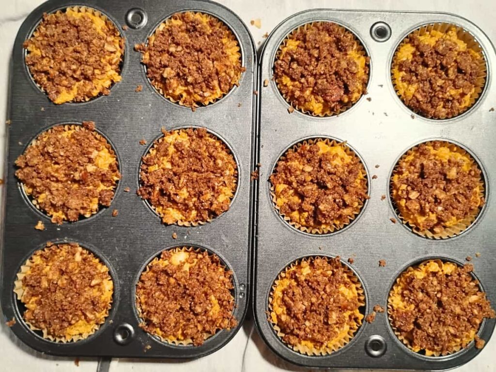unbaked muffins in fluted muffin sleeves in a muffin tray.