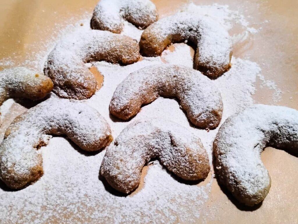 freshly dusted vanillekipferl on a piece of parchment.