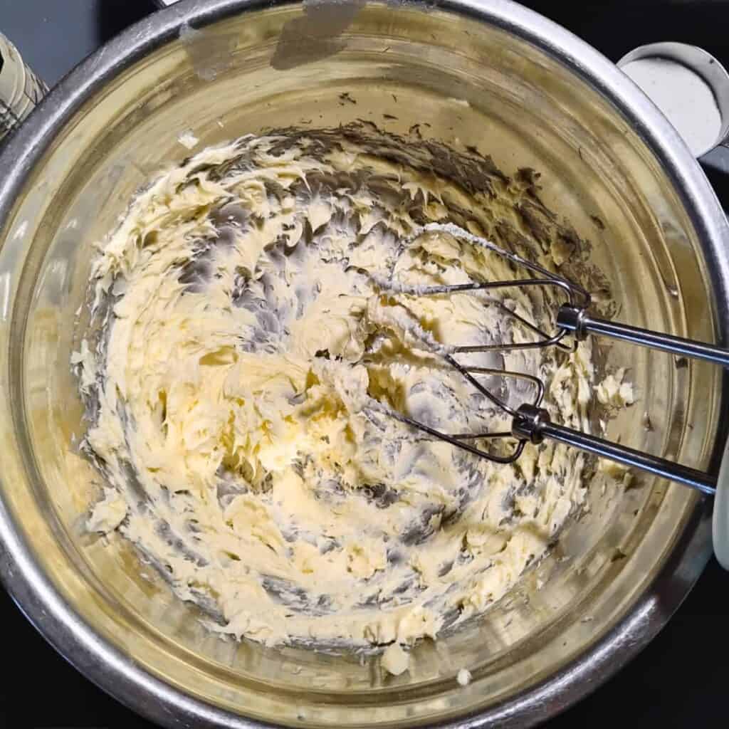creamed butter in a bowl with two beater bars.