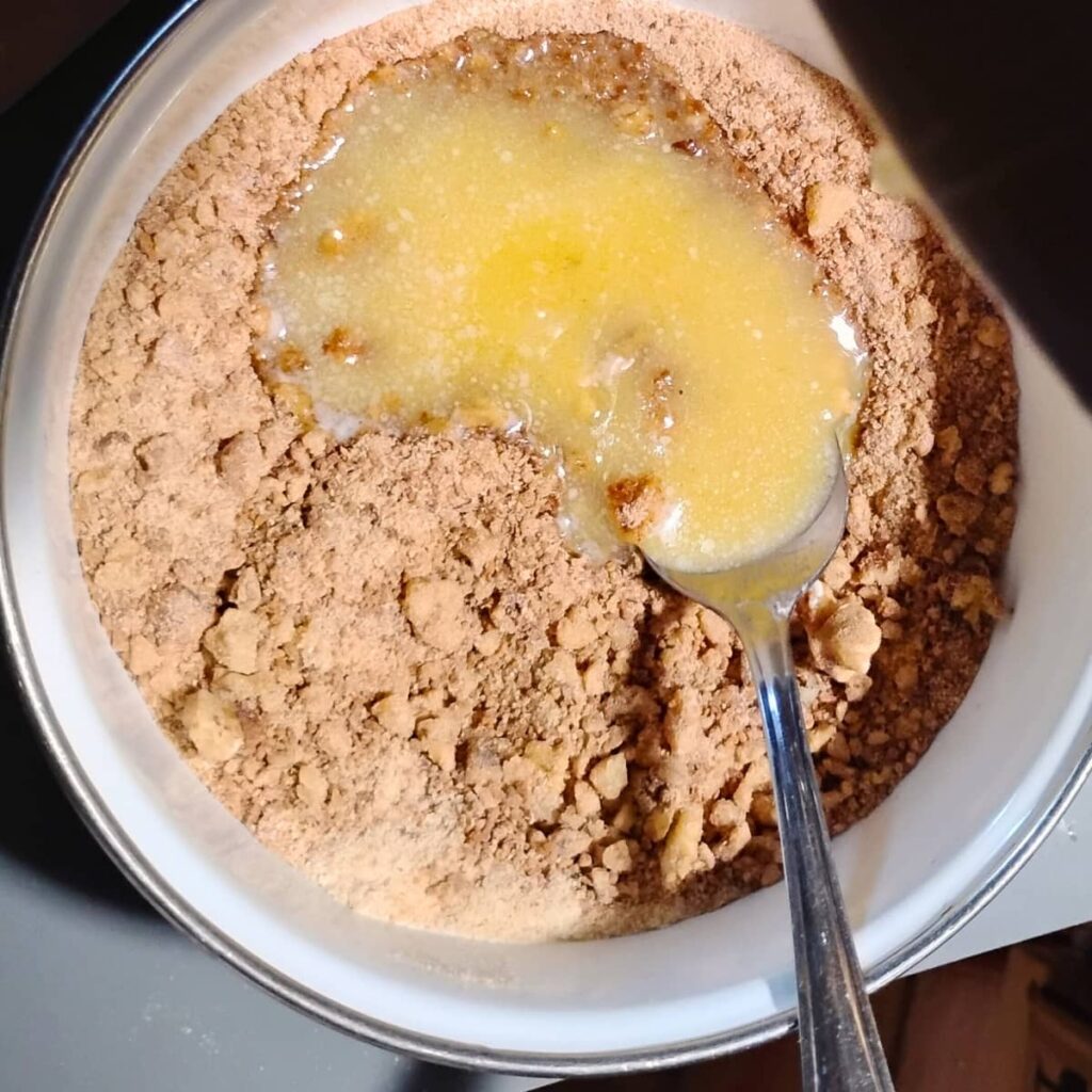 a small bowl filled with flour, walnuts and melted butter and showing a spoon.