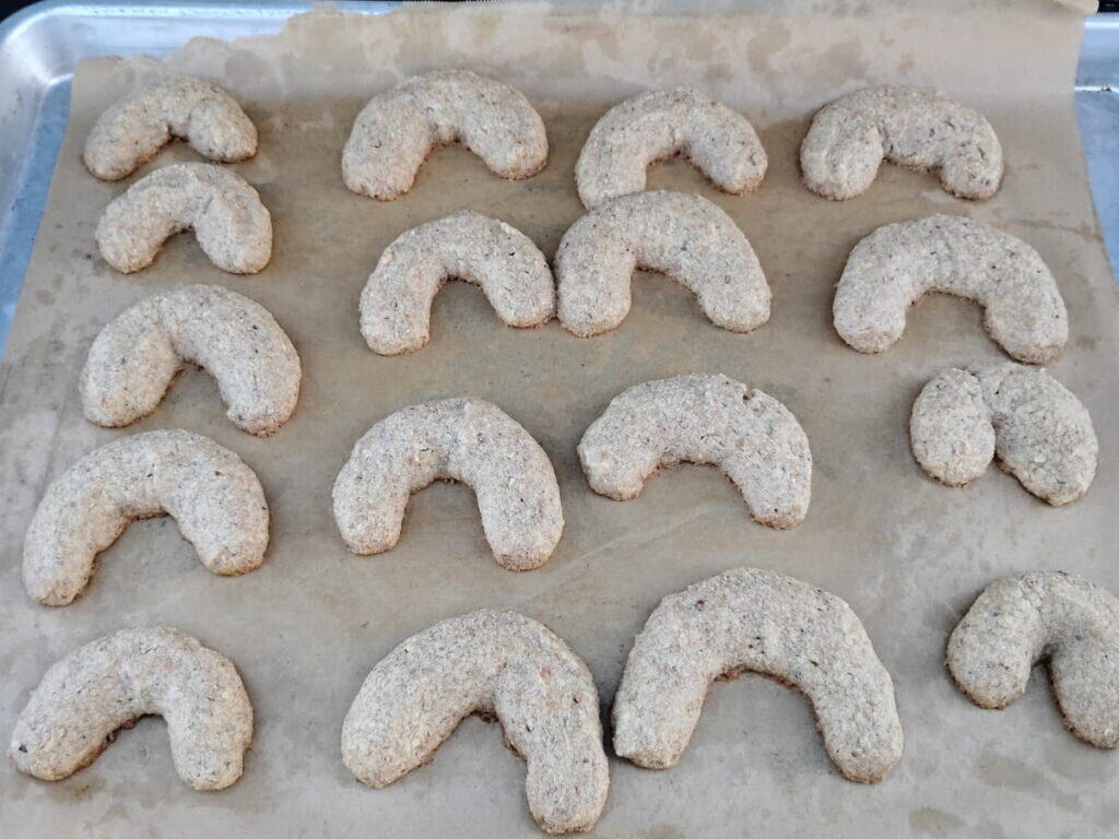 a baking sheet is filled with fresh baked vanillekipferl.