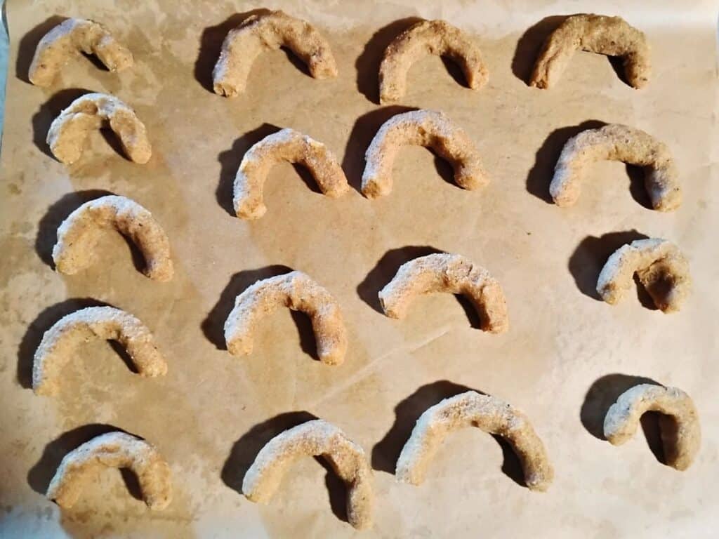 crescent shaped cookie dough on a parchment lined baking sheet