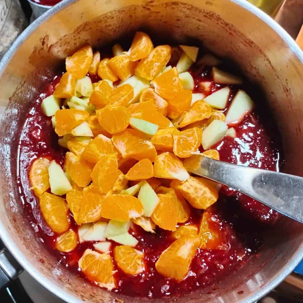 apples and orange sections are added to the cranberry sauce base.