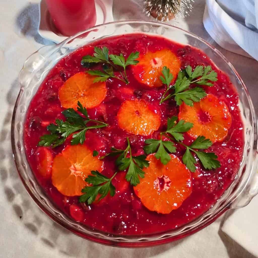 A pie plate with cranberry orange sauce and decorated with parsley.