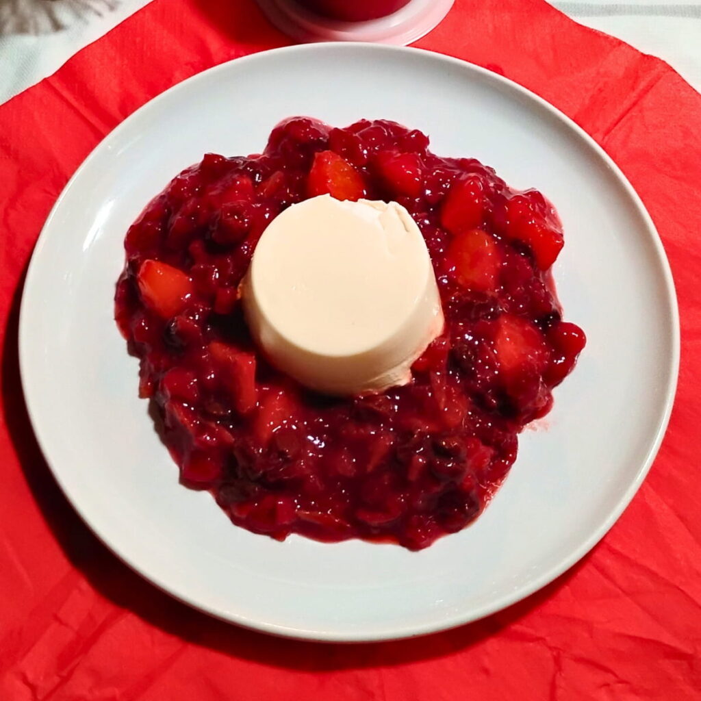 photo of a single serve portion of probiotic panna cotta surrounded with cranberry orange and hibiscus sauce.