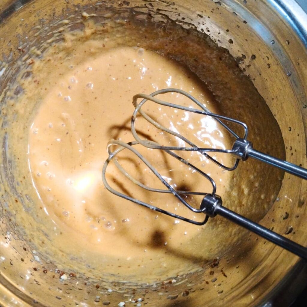two mixer beaters are shown over a bowl filled with some batter beginnings.