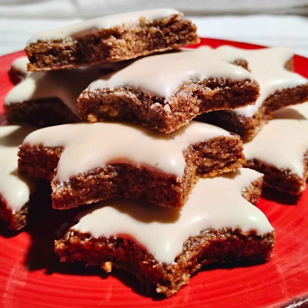 a pile of zimtsterne cinnamon star cookies on a red plate.