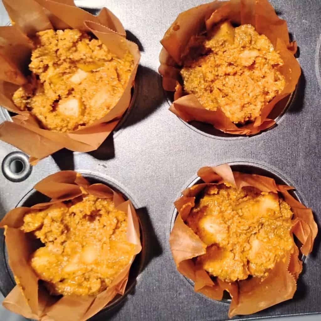 progression of assembly, first step shows a spoonful of batter added to the bottom of the muffin liners in a muffin pan.