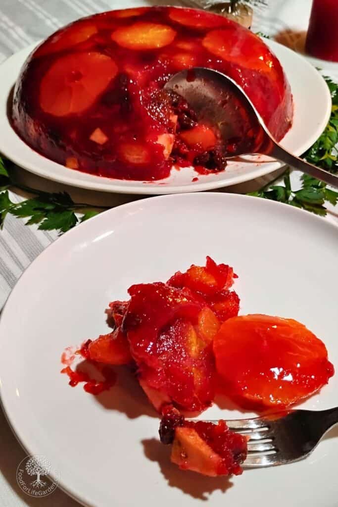 photo shows a plate with an un-molded gelatin cranberry orange salad and another plate in front of it with a portion of the salad and a fork with a chunk on it.