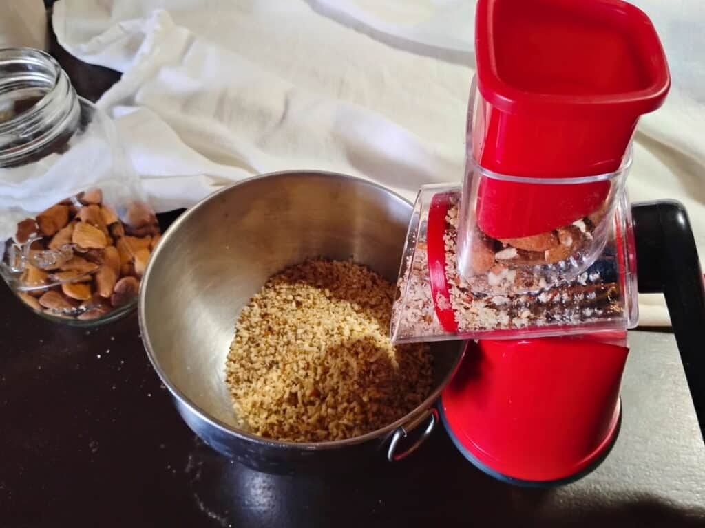 A geedel rotary grater grinding almonds into a coarse meal.