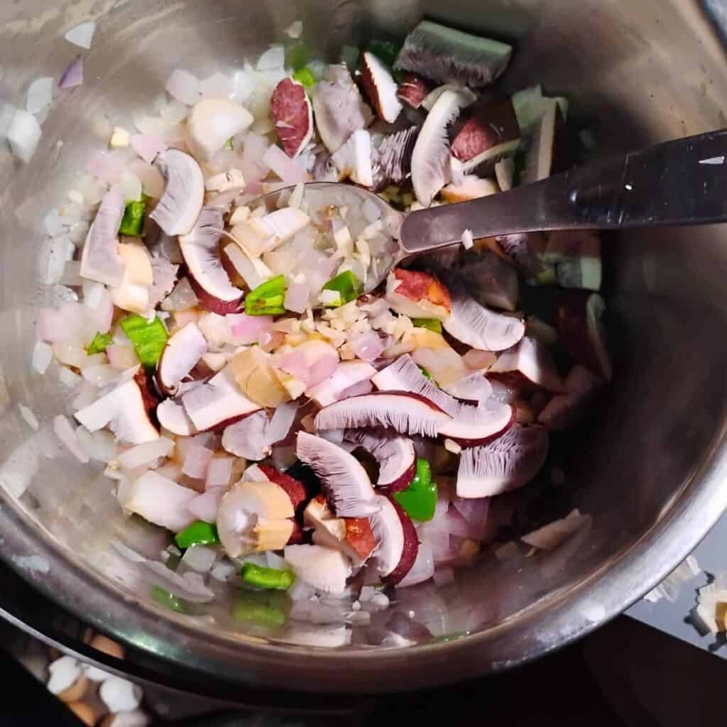 Mushrooms are added to the other sautéed ingredients in the pot