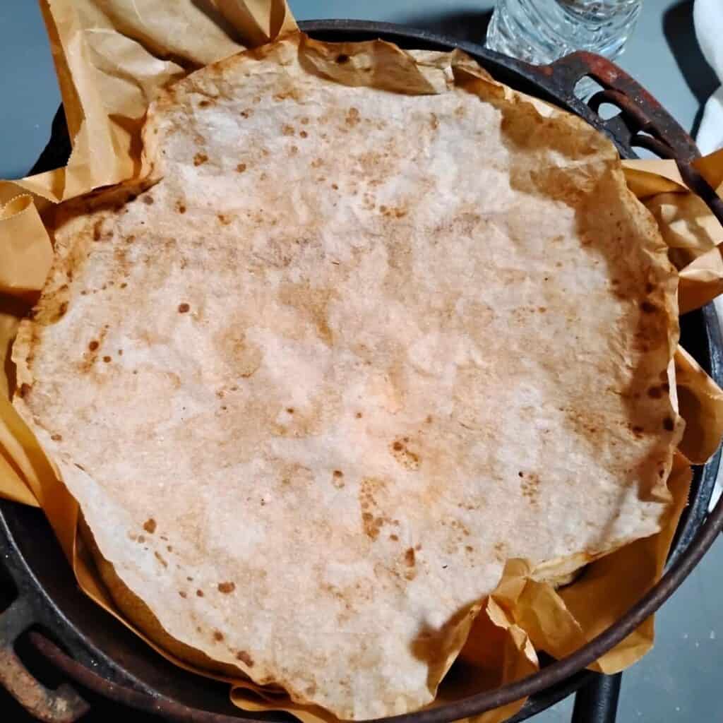 a dutch oven with bread dough in it and a piece of parchment paper on top. 