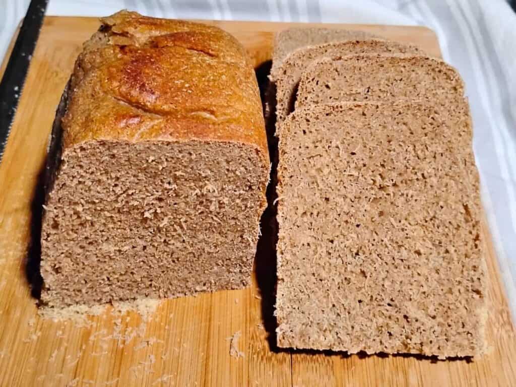 photo of half a loaf of sourdough rye bread with kamut and whey. part of it is sliced. 