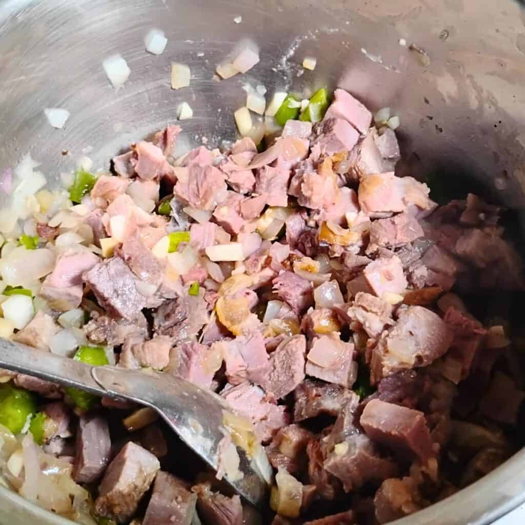 closeup of the ingredients in the pot, you can see onions, peppers, and ham.