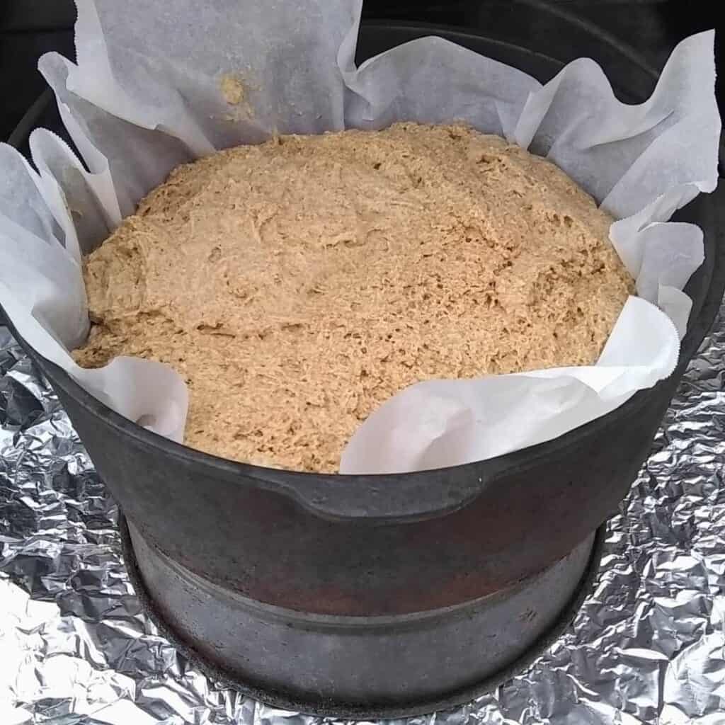 A dutch oven lined with parchment and bread dough inside it to get baked.