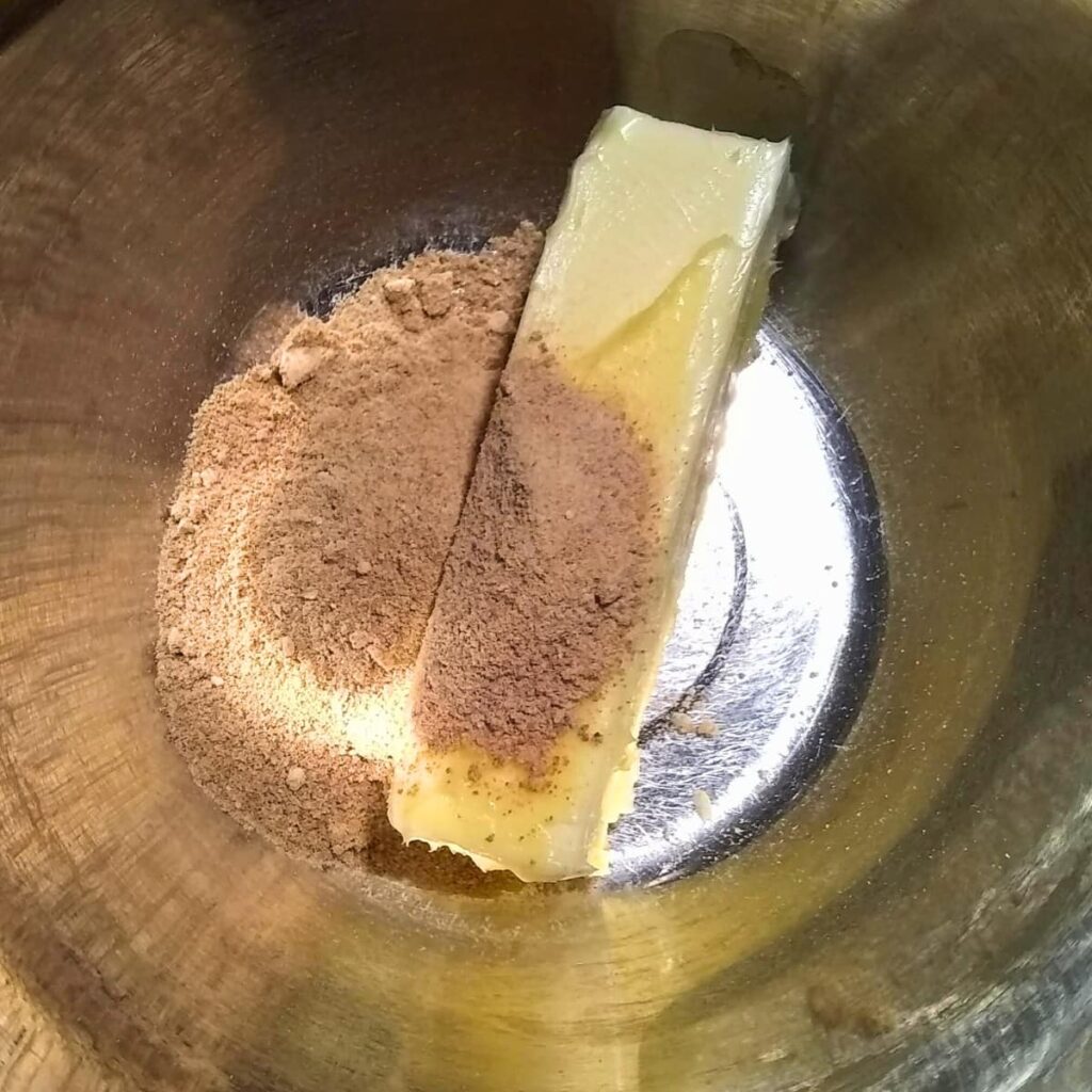 photo shows a stick of soft butter in a bowl with ground up panela sugar.