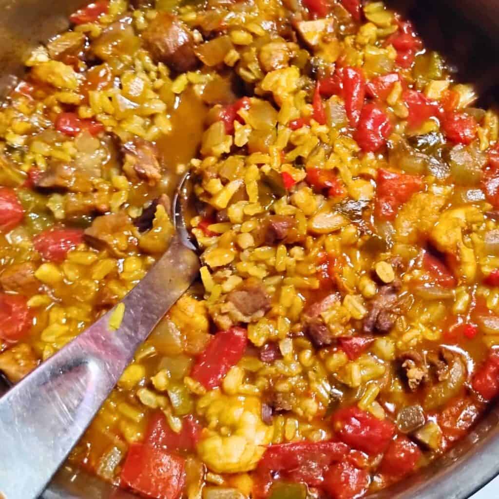 photo of a pot full of finished ham jambalaya with a spoon for serving it.
