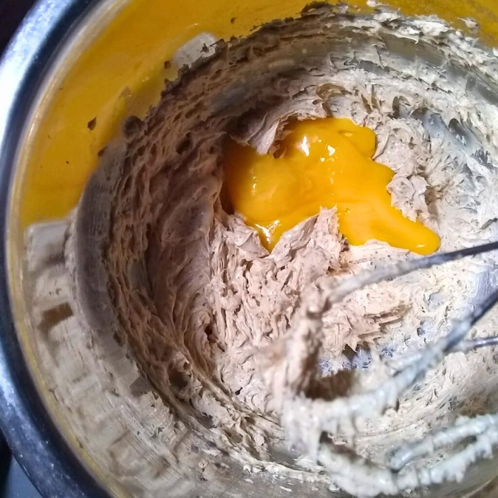 A bowl with creamed butter and sugar and an egg yolk.