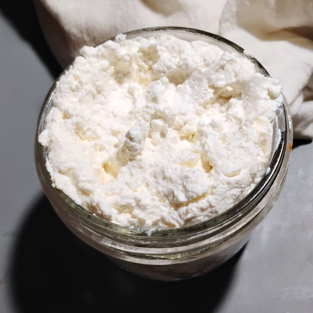 a mason jar filled to the top with fresh made soft cheese from sourdough starter. 