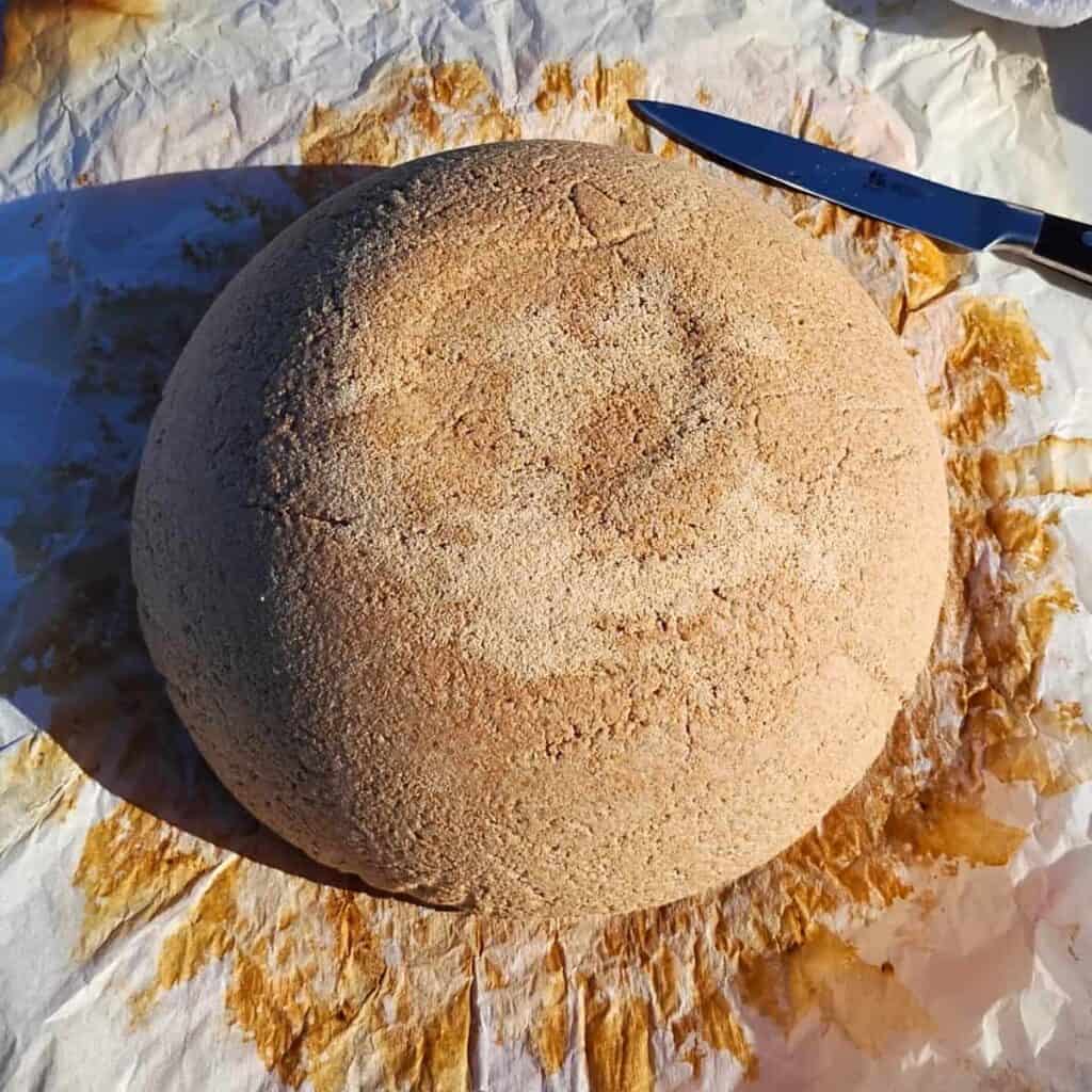 kamut and rye sourdough bread that has been roughly shaped, on top of a piece of parchment paper.