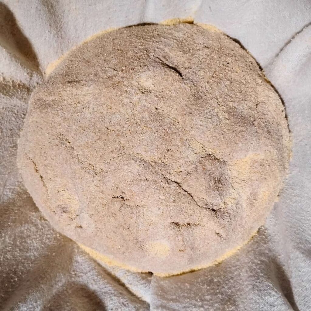a bread dough covered with flour on a floured cloth.