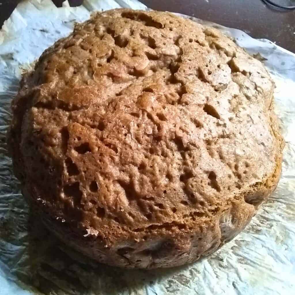 a fresh baked sourdough rye bread loaf on a piece of parchment. 