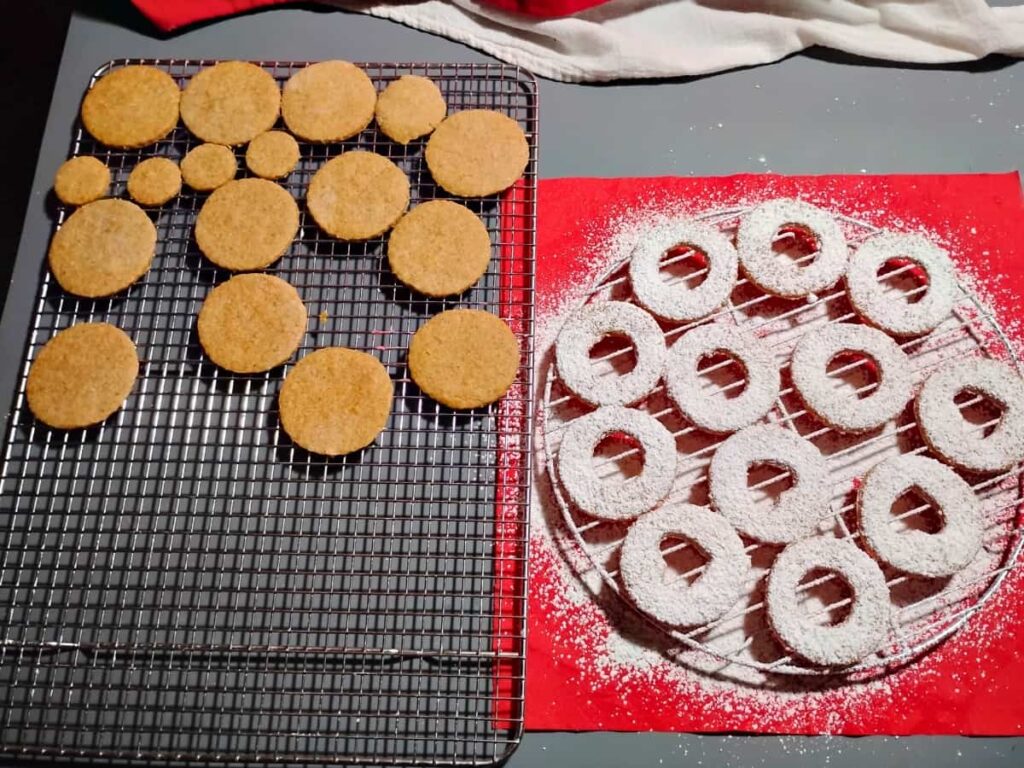 the cookies are finished baking and the bottoms are sitting on a cooling rack while the tops are on a separate rack and just got dusted with powder sugar.
