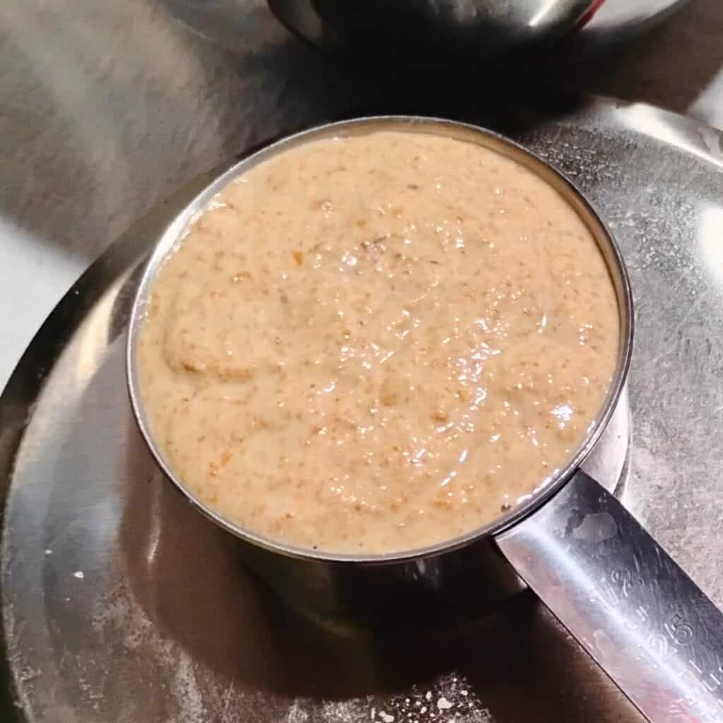 sourdough getting weighted in a measuring cup to go into the mixing bowl. 