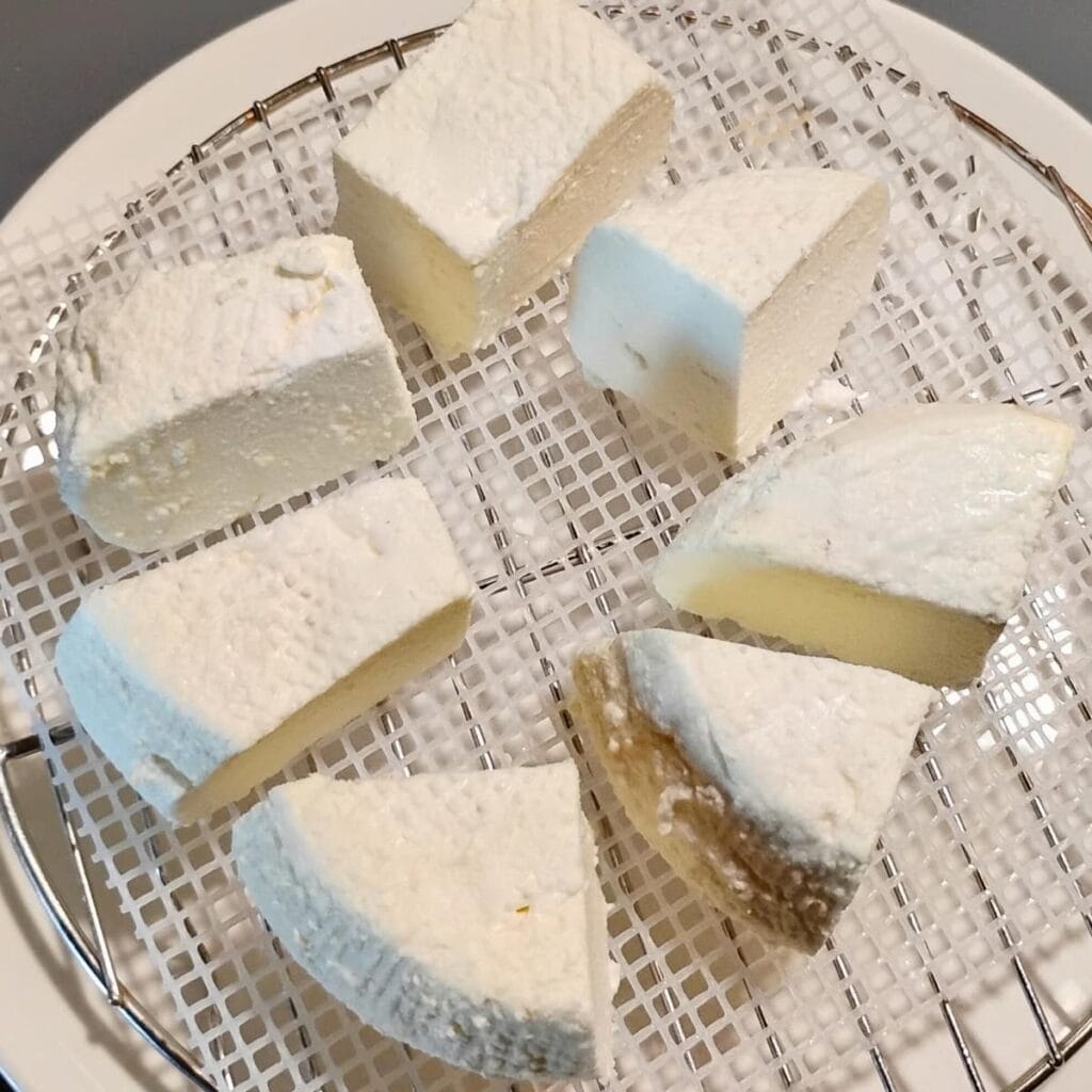 photo of feta cheese chunks on a drainage mat over a plate.