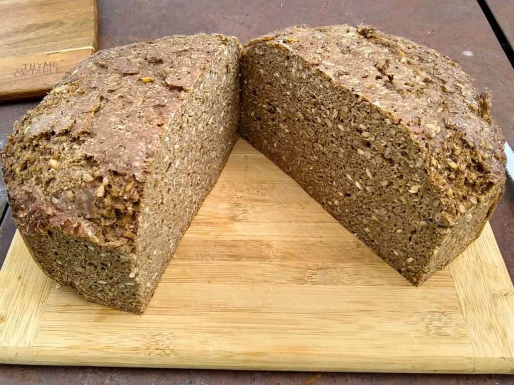 a rye and spelt bread loaf cut in half on a cutting board.