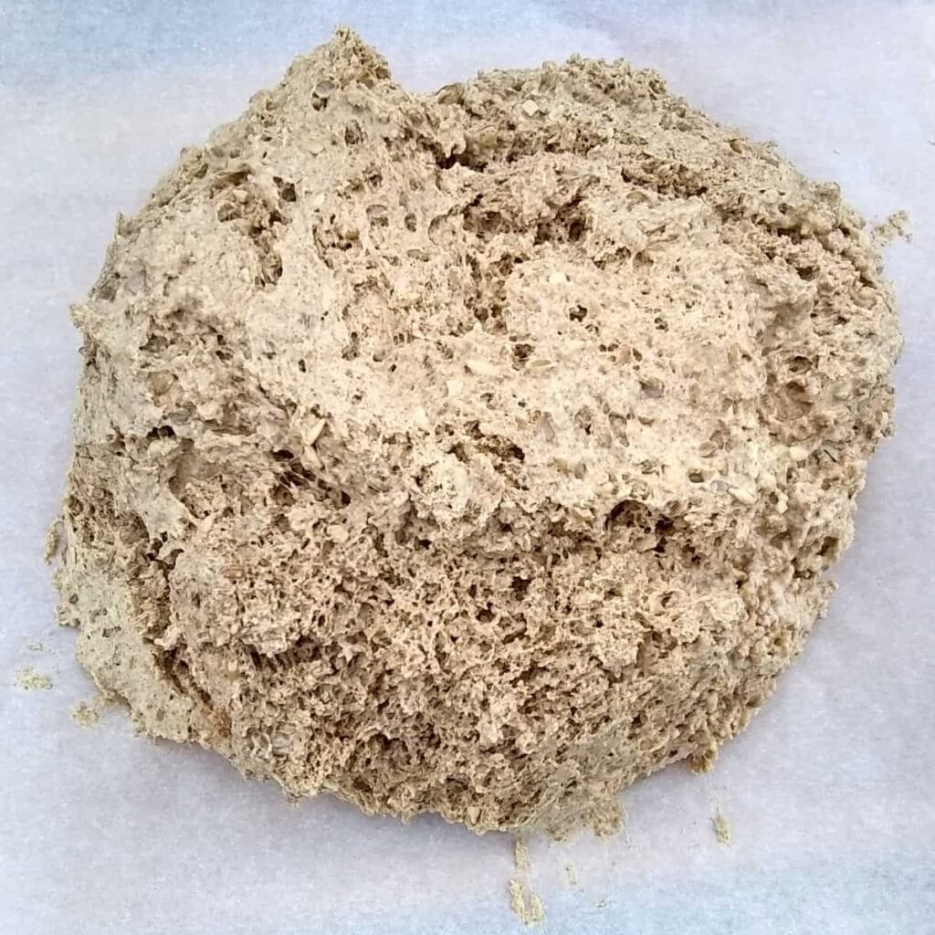 seeded rye bread dough on top of a piece of parchment.