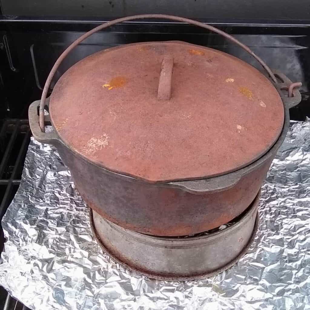 photo of a pot getting heated in a bbq grill. it is sitting on top of a cake ring.