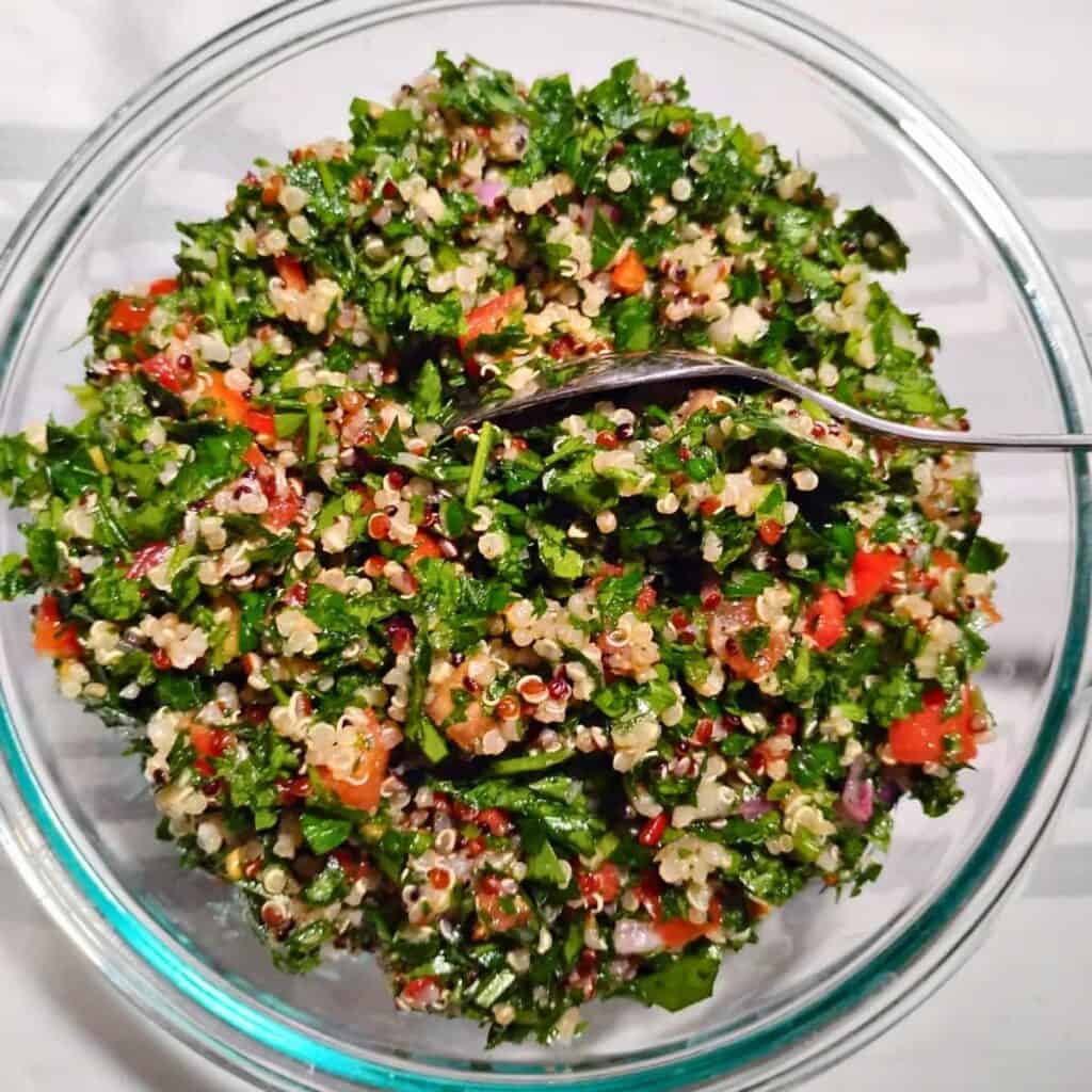 a glass bowl filled with tabouli salad with quinoa.