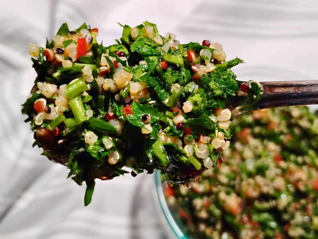 Spoonful of quinoa tabbouleh with a bowl full of it below. 