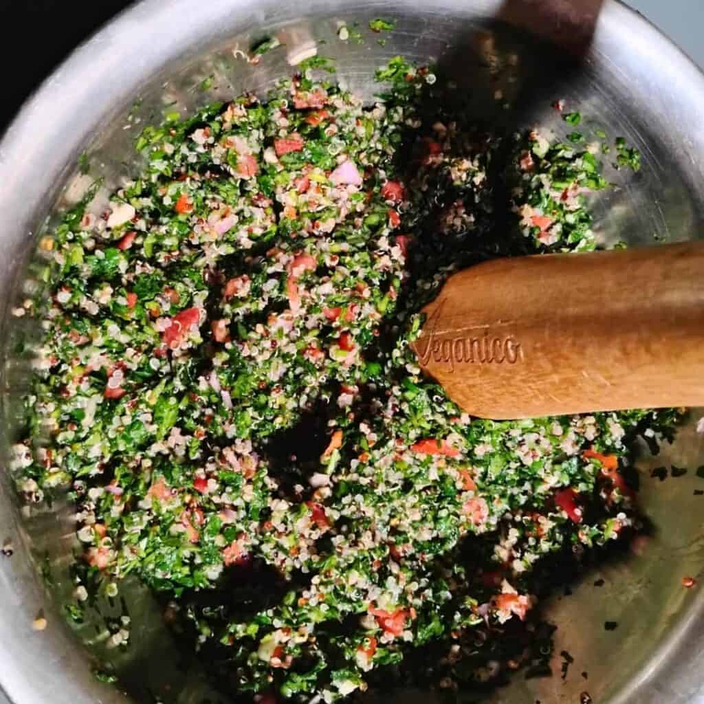 a bowl filled with tabouli salad for fermenting and a wooden pickle packer stomping it down. 