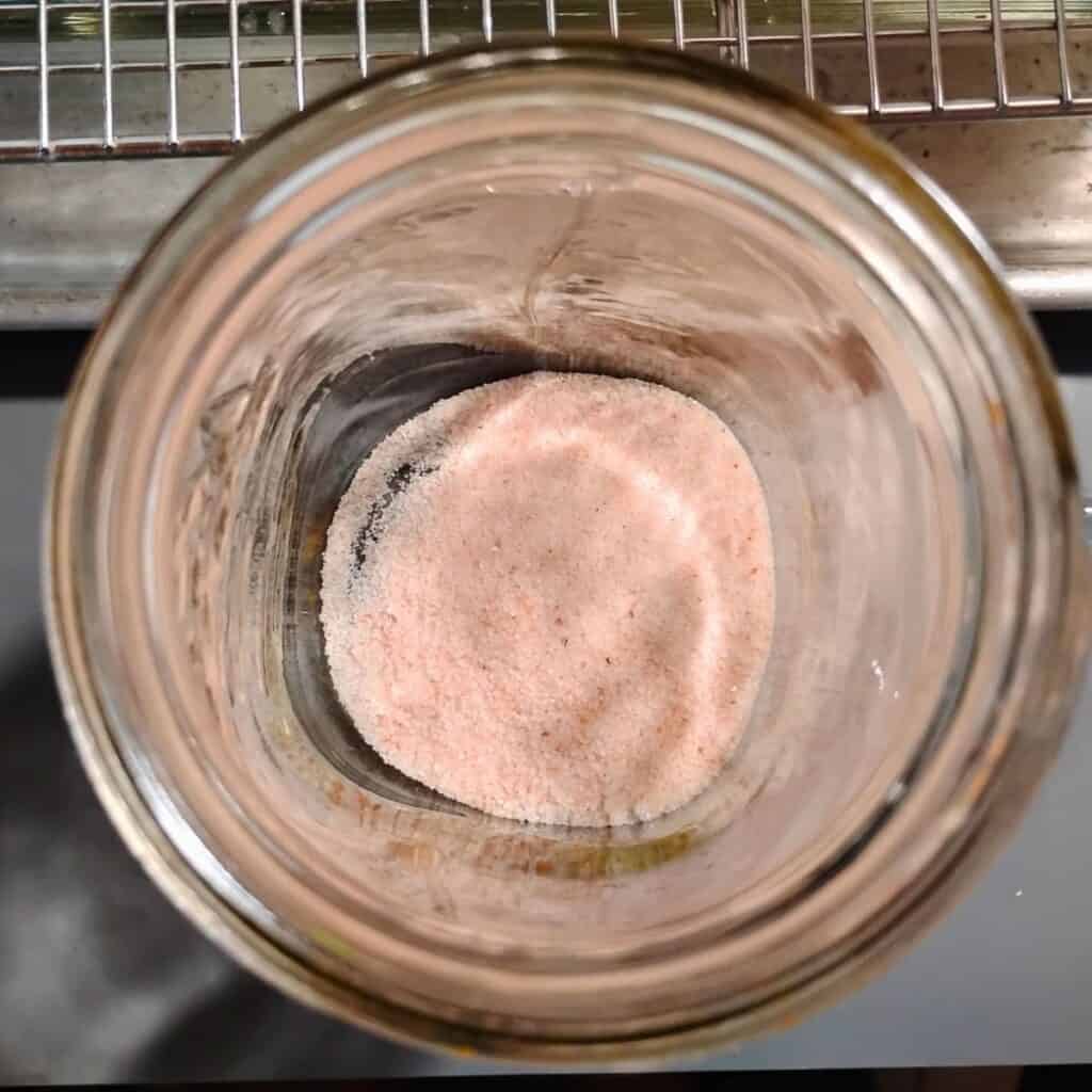 A mason jar with some salt in the bottom of it.