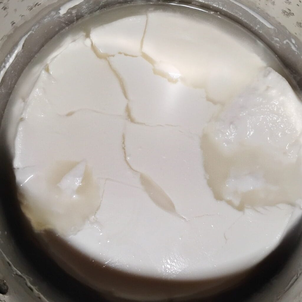 a mass of cheese curd in a pot that needs to be cut. It has some lines from a previous cut.