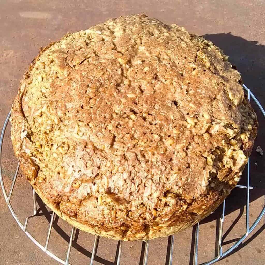 photo of a loaf of seeded rye bread on a cooling rack.