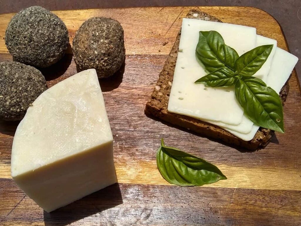 a chunk of bel paese cheese, some belper knolls and a slice of seeded rye bread with slices of bel paese cheese on top.