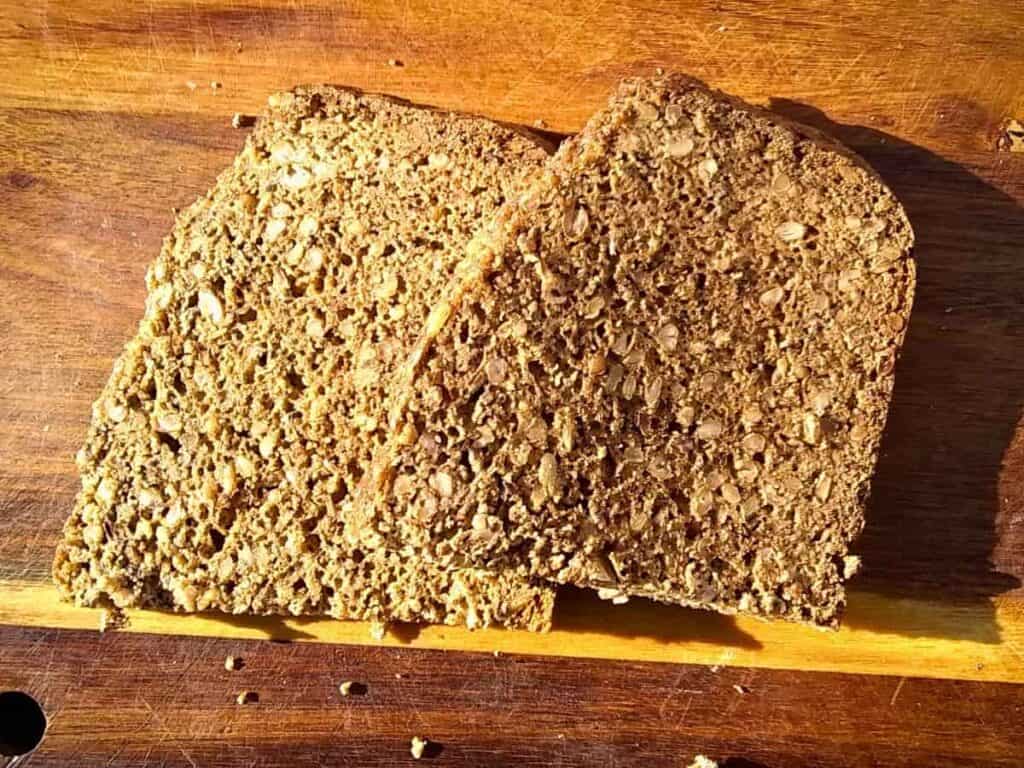 two slices of sourdough no-knead seeded rye and spelt bread on a cutting board.